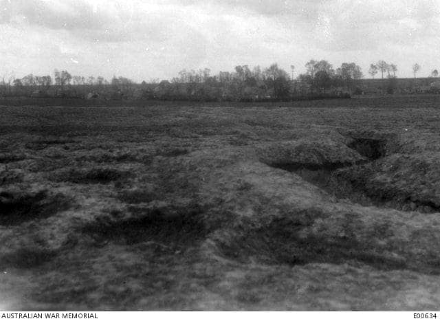 Photographie de guerre en noir et blanc : les champs retournés devant les arbres du village, le 14 mai 1917