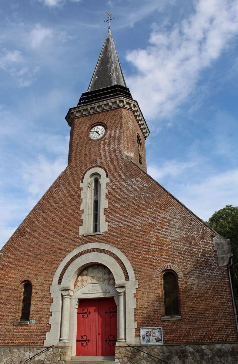 La façade de l’église Saint-Vaast, en brique, avec sa porte rouge et son clocher